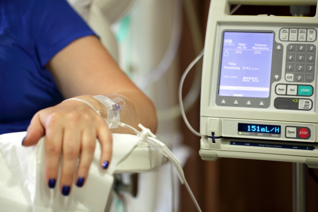 alt="Infusion pump feeding IV drip into patients arm focus on needle"