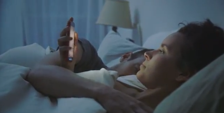 alt='Woman Using Smartphone in Bed"
