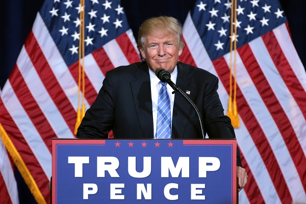 Donald Trump smiling behind Pence sign 