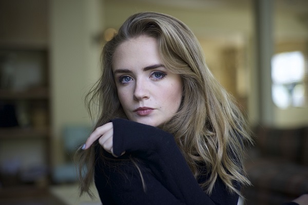 Young blonde woman looking at the camera in pensive mood.