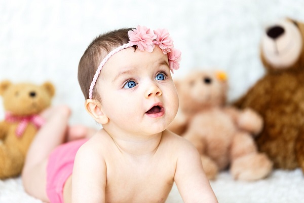 Beautiful baby girl among stuffed toys